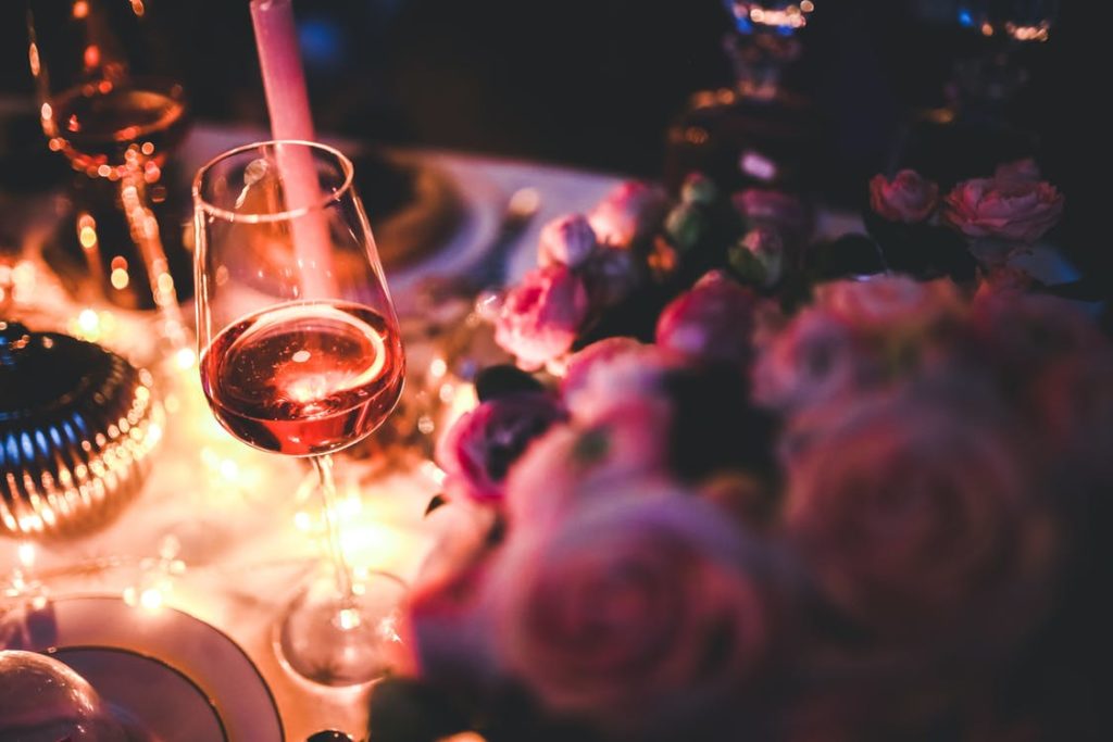 Wine glass and a candle on a table surrounded by flowers