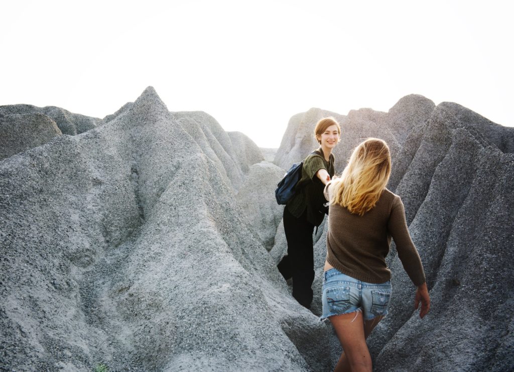 Woman helping person through mountain trail