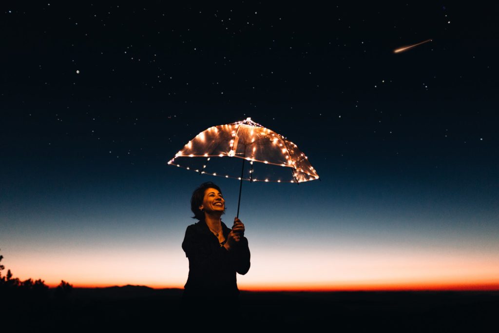 Woman with light up umbrella smiling at night time