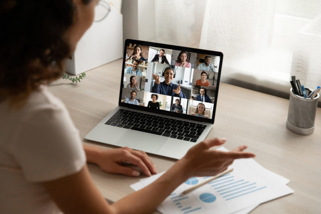 Back view of woman on team video meeting with diverse colleagues.
