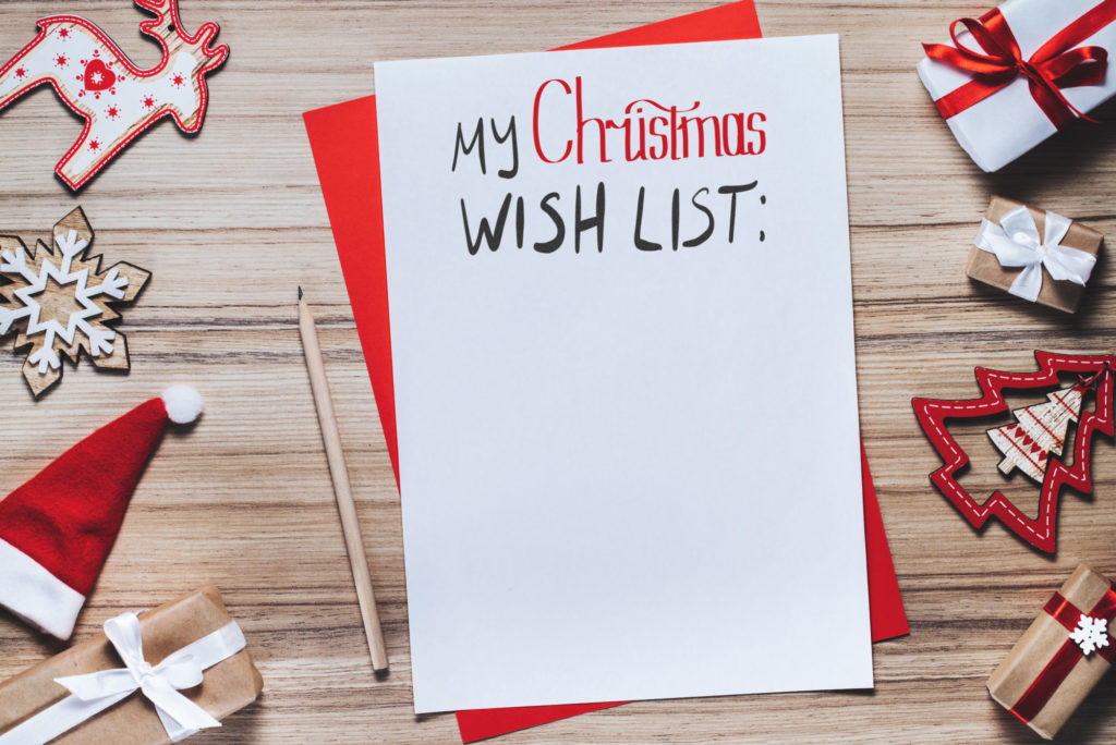 White piece of paper with 'My Christmas Wish List' written on it, surrounded by festive decorations. 
